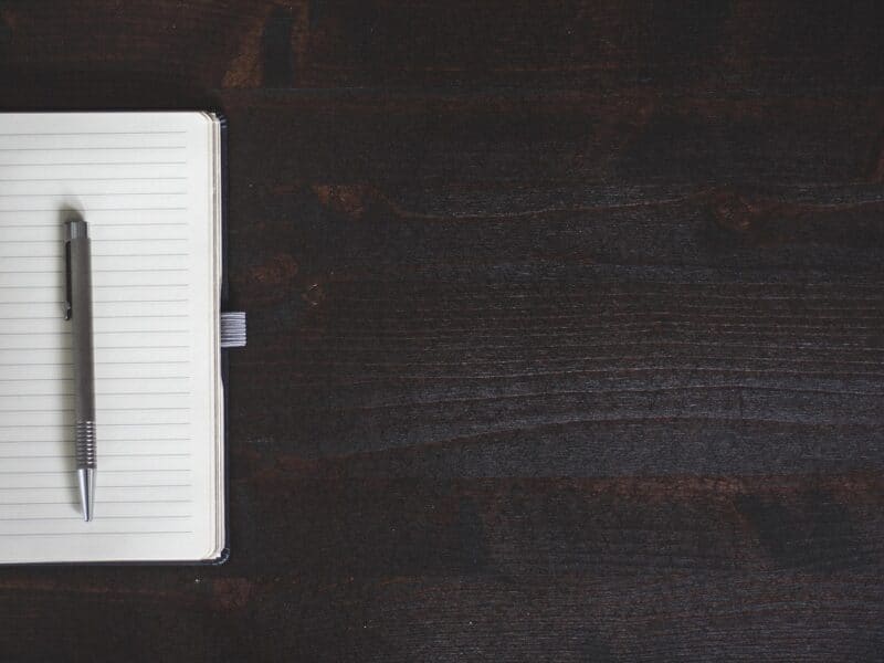 Notebook and pen on a dark wooden desk