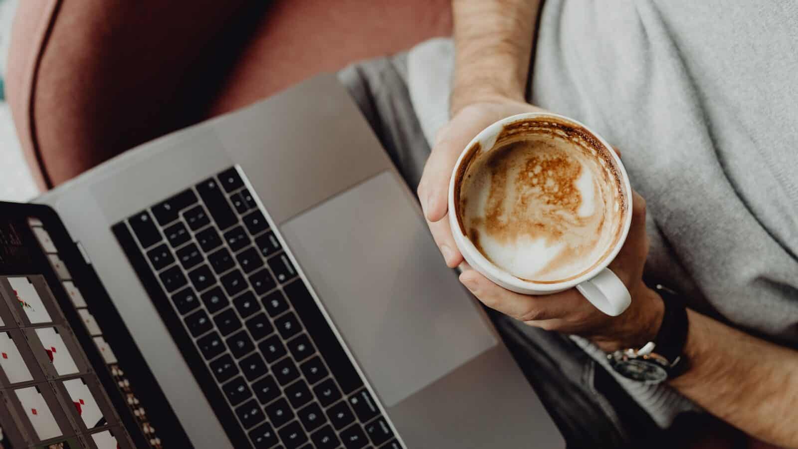 Person working on a laptop with coffee, related to Estonia company formation costs.